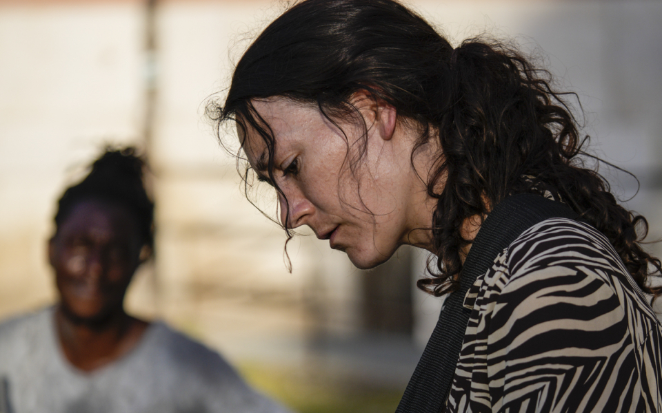 Teresa ist eine weisse Frau mit langen braunen Haaren, die zu einem Pferdeschwanz gebunden sind. Sie trägt eine schwarz-weiss gestreifte langarmige Bluse. Sie spielt auf einer roten Gitarre mit schwarzem Umhängegurt. Im Hintergrund sitzt ein dunkelhäutiger zweiter Musiker und schaut zu ihr hinüber.